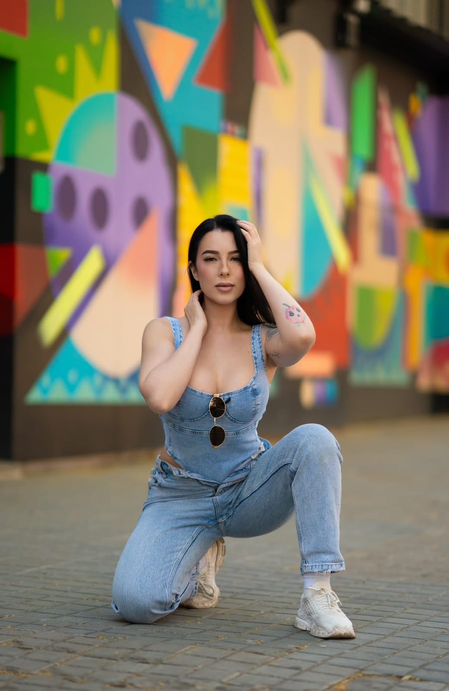 Sini apoyada sobre una rodilla delante de un mural de colores en Barcelona